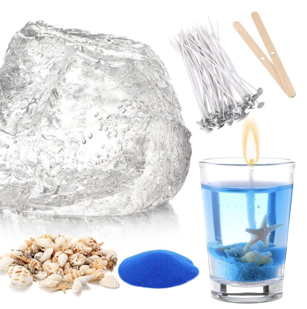 A collection of candle-making supplies: a large block of clear gel wax, wicks, wooden sticks, tiny seashells, blue sand, and a completed gel candle in a glass with layers of blue sand, seashells, and dried flowers. The masterpiece is topped with a starfish and crowned by a graceful flame.